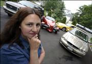 Melissa Senatore stands in the driveway of her home in Riverhead, N.Y., with four of the five vehicles her family owns. Senatore was paying more than $14,000 a year for auto insurance on the cars, but has gotten the bill down to near $10,000.