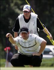 Jason Gore, bottom, lines up his putt on the second hole with caddie Lewis Puller. Gore shot 2-over 72 Saturday in Pinehurst, N.C., and is three shots out of the lead.