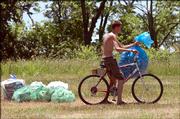 Ryan Shaughnessy, 19, Lawrence, helps with cleanup at Clinton Lake State Park after the festival. He peddled around the campgrounds Monday morning, filling his bag with cans.