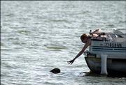 Janet Frakes, Shawnee resident, reaches for her floating straw hat Wednesday afternoon at Clinton Lake. Frakes had just purchased the hat yesterday to keep the sun off her face while she and her husband boated, and she was able to retrieve it successfully.