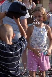Clay Lister, 7, shakes confetti from his hat as older sister Erayna Lister, 9, smiles at her handiwork. Clay repaid her for the confetti-filled egg she broke over his head by throwing another one at her. The two children were at the St. John's Fiesta Mexicana Friday night with the rest of their family, who are parish members and attend the fiesta almost every year.