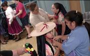 Inez Silva, 9, gets help with her costume from mother Caro Silva. During the 24th annual St. John's Fiesta Mexicana, the dancers used one of the church's classrooms as a makeshift dressing room. Their performance Friday night at the fiesta required three costume changes, which Silva said the girls had mastered at only three minutes apiece.