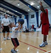 Six-year-old Reser Hall shoots as his father, Dick, of Prairie Village, left, and Kansas University sophomore Darnell Jackson, right, watch. The pair attended KU coach Bill Self's Parent-Child Basketball Camp on Saturday at Horejsi Center.