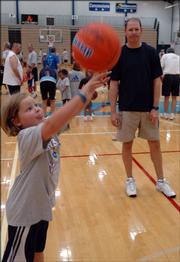 Former Kansas University basketball player Chris Piper watches his daughter Madison, 6, shoot the ball during drills. They attended the Bill Self Parent-Child Basketball Camp on Saturday at Horejsi Center.