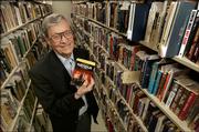 James Gunn, director of the Center for the Study of Science Fiction at Kansas University, holds one his own books as he stands among a small portion of the center's holdings on the Lawrence campus.