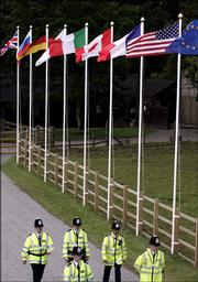 Police officers walk by the flags of the G8 leaders in front of the Gleneagles Hotel near Auchterarder, Scotland. Scottish police on Tuesday promised zero tolerance for troublemakers at protests planned to coincide with the opening of the summit of leaders of the G8 group of wealthy nations, which begins today.