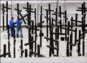 Workers tear down the crosses of the private Berlin Wall memorial near the former allied Checkpoint Charlie. Following long legal proceedings after the lease for the site expired in 2004, the memorial was dismantled Tuesday. The 1,067 crosses stood for the number of victims killed at the border from 1961 to 1989, according to the figures of the Checkpoint Charlie museum, which built the memorial.