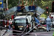 A forensic officer walks next to the wreckage of a double decker bus with its top blown off and damaged cars scattered on the road at Tavistock Square in central London. A series of explosions blamed on Islamic terrorists tore into at least three London subway trains and a double-decker bus Thursday, killing dozens and injuring hundreds.
