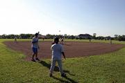 10-U Rebels coach Mike Willoughby prepares to hit the ball while his team stands ready at the Rebels practice field west of Lawrence on Thursday. The field is on a friend of the team's property.