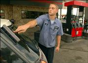 Mat Fuller washes the back window for a customer while filling up the car with gasoline at Westside 66 gas station at Sixth Street and Schwarz Road on Thursday. The service station is the only full-service gas station in town, where workers fill the car with fuel, wash windows, check the oil and check and inflate the tires.