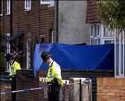 Policemen observe two minutes of silence, in honor of the victims of the July 7 London terrorist attack, outside a house being searched Thursday in connection with the attack, in Aylesbury, England. The police raided the house Wednesday night.