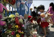 Sophie Martinez, 2, right, and Leslie Cortez, 7, place flowers at a memorial for 19-month-old Suzie Marie Pena on Friday in the Watts section of Los Angeles. It's been 40 years since a deadly riot in Watts came to symbolize America's urban despair. But tensions flared anew this week after police fatally shot the 19-month-old and her father, who clutched the girl as he fired on police responding to a 911 call.