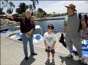 Author Richard Louv tells Tim Schultz, right, and his 6-year-old son, Nicholas, where to find trout and bass at the Miramar Reservoir in San Diego.