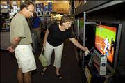 Lawrence residents Kerry and Becky Schneider browse through big-screen televisions Friday afternoon at Best Buy, 2020 W. 31st Street. With advances in high-definition television, many consumers are turning their backs on smaller TVs and setting their sights on larger models, despite the higher electricity bills.