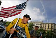 Lance Armstrong flies the colors during a victory parade on the Champs-Elysees after winning his seventh straight Tour de France. Armstrong claimed his unprecedented victory Sunday in Paris.