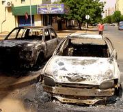 People look over the remains of cars destroyed by protesters who took to the streets in Khartoum, Sudan, after the announcement of the death of former rebel leader and First Vice President John Garang in a helicopter crash. Garang supporters tore through the capital in riots that left at least 49 people dead, smashing cars and shops and angrily blaming the government for their hero's death.