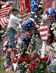 A man who identified himself only as a former Marine, adds a memento to the ever-growing makeshift memorial on the fence surrounding the 3rd Battalion, 25th Marines headquarters in Brook Park, Ohio. The suburban Cleveland-based battalion was hard hit with casualties this week in Iraq.