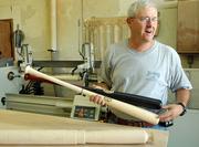 Calvin Ledbetter, co-owner of Lawrence's Diamond Cabinetry, also makes a line of Diamond bats for minor-league players, including his son Curtis, a Lawrence High product now in the Seattle Mariners' minor-league system. A block of maple, foreground, is turned on a lathe, background, before the brand goes on.