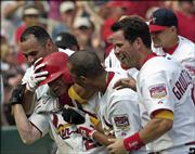 St. Louis's David Eckstein, wearing batting helmet, is mobbed by teammates, from left, Albert Pujols, John Rodriguez and Mark Grudzielanek after hitting a walk-off grand slam against Atlanta. The Cardinals won, 5-3, Sunday in St. Louis.