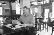 Bobby Douglass, one of the new owners of the Eldridge Hotel, 701 Mass., studies a new menu in the renovated bar area. The former Kansas University and NFL athlete was among alumni who bought the Eldridge, reopening it in May.