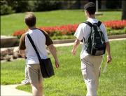 Kansas University students walk in front of Strong Hall while wearing a one-strap messenger bag, left, and a two-strap backpack.