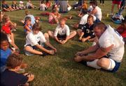 Senior linebacker Banks Floodman, right, leads a group of children through stretching exercises at the conclusion of practice. As part of Kids Day, youngsters were allowed to watch the last 30 minutes of practice and participate in stretching with KU players Sunday night at the practice fields near Hoglund Ballpark.
