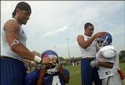 Junior defensive back Kenneth Thompson, left, helps 4-year-old Jevon Thompson with his helmet, while sophomore running back Gary Green, right, helps Malik Thompson, 9, with his lid.