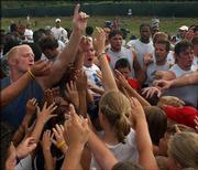 Senior linebacker Nick Reid fires up a group of youths in a huddle during Kids Day. An estimated 700 fans took part in the festivities, during which youngsters watched the final minutes of practice and stretched with the Jayhawks, then mingled for autographs.