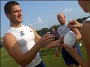 Kansas University senior linebacker Darren Rus prepares to sign an autograph for a fan during Kids Day. An autograph session was part of the Kids Day activities Sunday on the KU practice fields.