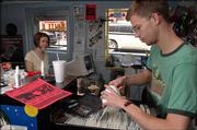 Micah Adams, who works at Game Guy, a video game store at 7 E. Seventh St., locates a video game for a customer. More college students are going back to video games they played as children rather than the high-tech versions of today.
