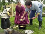 Robbie Walker, Hoyt, puts a piece of cornbread on Arlene Walker's plate, also from Hoyt, during a Civil War re-enactment in August 2004. Events for this year's Civil War on the Western Frontier will take place at the Watkins Community Museum of History, Lawrence Public Library, South Park and other area locations.