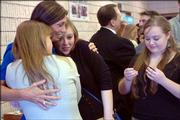 Carol Wilson, second from left, mother of Kimberly Wilson, is hugged by Carrie Mayhew, left, and Lauren Mayhew, 19, as Rebecca Mayhew, 17, waits at right to extend condolences Monday afternoon at the Free Methodist Church in Lawrence. Kimberly Wilson, 15, died accidentally last Tuesday at her Lawrence home while playing a "pass out" game alone.
