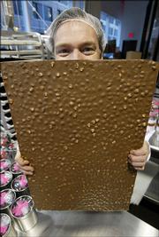Chocolatier Jacques Torres holds a large sheet of milk chocolate almond bark at his Chocolate Haven in New York in this Jan. 27 file photo. While something in cocoa beans may be good for your heart, that is no reason to load up on chocolate bars or brownies. Cocoa beans have antioxidant compounds called flavanols, and a growing pile of scientific research suggests that flavanols do good things to blood vessels. Trouble is, flavanols make chocolate and cocoa taste bitter, and confectioners have spent years perfecting ways to remove the pungent flavor.