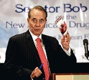 Former U.S. Sen. Bob Dole holds up a pamphlet on Medicare prescription drug coverage as he addresses a gathering Tuesday at the Florida Conference on Aging in Orlando, Fla. Dole said senior citizens on Medicare could save thousands of dollars each year if they simply took the time to fill out an easy four-page application.