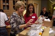 Lisa Buchholz, center, and Becky Hubbell pack medical supplies in preparation for a trip to Romania. Both will travel in early September with a group from the Medical Missionary Foundation to serve as pharmacists for children and families for a week. They are pictured at Hubbell's home in Leawood.