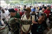 A Louisiana National Guardsmen holds back residents as they gather outside the Louisiana Superdome in New Orleans on Sunday. The Superdome opened Sunday to residents of New Orleans who are seeking shelter from Hurricane Katrina, which is expected to make landfall today.