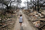 Rhonda Braden walks through the destruction in her childhood neighborhood Wednesday in Long Beach, Miss. Hurricane Katrina destroyed the area where her father lived.