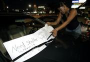Hurricane Katrina evacuee Ronda Caldoron, 35, from New Orleans, adjusts some signs on her car in a parking lot across the street from Reliant Stadium and the Astrodome in Houston. Caldoron was turned away from staying at the Astrodome, which will house only people who were stranded at the dank, sweltering Superdome in New Orleans, where the water was rising, the air conditioning was out and toilets were broken.