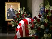 The coffin bearing the body of Chief Justice William H. Rehnquist lies in the Great Hall of the U.S. Supreme Court, under the view of his official portrait painted in 1994 by artist Thomas Loepp.