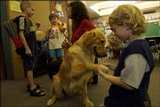 Schwegler School first-grader Brandon Taylor, 6, introduces himself to his new classmate, a training dog named Gemini, as his new teacher Lisa Clark speaks with two of her former students, James and Jasmine Harader-Ellett, Aug. 16 during new student orientation at the school.