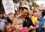 Anti-war activist Cindy Sheehan, second from right, shares a moment with the Rev. Jesse Jackson, center, during an anti-war protest march in Washington. At right is singer Joan Baez. Tens of thousands of marchers on Saturday protested the war in Iraq.