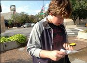 Alek Joyce, a Central Junior High School eighth-grader, uses a handheld GPS unit to find a geocaching site near Eighth and Massachusetts streets.