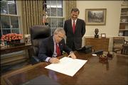 In this photo provided by the White House, President Bush signs the commission appointing John Roberts, right, as the 17th chief justice of the United States before swearing-in ceremonies.