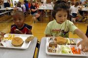 Jarelle Dye, left, and kindergarten classmate Talima Harjo sit down for a school lunch last week at Kennedy School. Lawrence cafeterias allow students to have several meal options, and that self-serve philosophy is working well at Kennedy School, says kitchen manager Sharon Mitchell. "The kids today are really making good choices," she says. Others are not so sure.