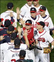Atlanta catcher Brian McCann, center, celebrates with teammates. The Braves defeated the Houston Astros, 7-1, Thursday night in Atlanta to even their National League series at one game apiece.
