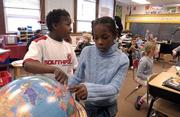 After a few moments of searching, Pinckney School fourth-graders Xavier Newman, left, and Khadijah Lane point to Iraq on a globe.