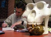 Novelist Eric Penz, of Seattle, signs one of his books for a buyer Saturday at the Texas Bigfoot Conference in Jefferson, Texas. The skull is a creation based on calculations from the jaw fossil, Penz said.