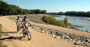 Marcus and Kathy Bassett, of Topeka, ride their bikes on the Kansas River levee bike trail below the Bowersock Dam on Friday.
