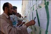 Adel Lami, left, chief of the Independent Electoral Commission in Iraq, monitors the work of election employees Sunday in Baghdad, Iraq, as they enter data from the constitution referendum. Iraq's constitution seemed assured of passage Sunday despite strong opposition from Sunni Arabs, who turned out in surprisingly high numbers in an effort to stop it.
