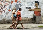 People pass graffiti Saturday in Rio De Janeiro, Brazil. Brazilians will vote today on whether they want to ban the sale of firearms. Brazil ranks second in deaths by guns with 21.72 per 100,000 people a year, behind only Venezuela with 34.3 gun deaths per 100,000.
